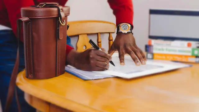 A person writing at a table; illustrative photograph.