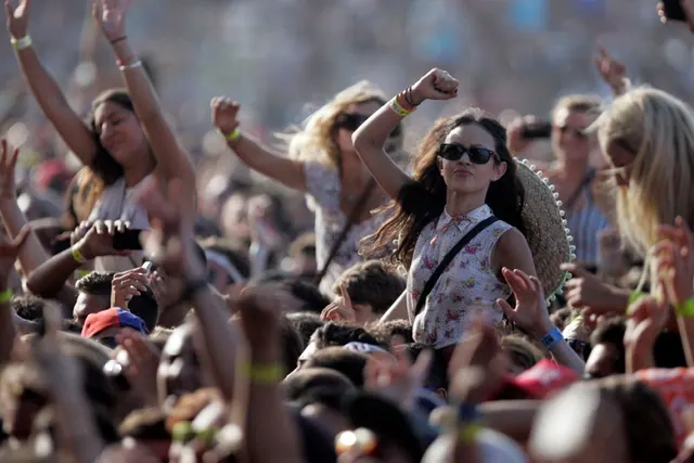 People raising their hands at an outdoor event in an archive photograph.