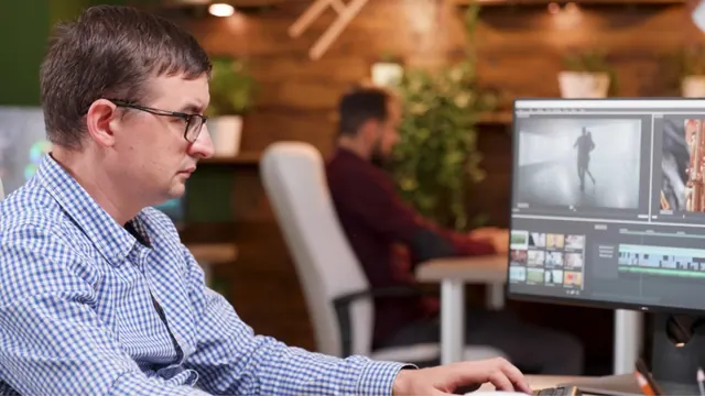 Stock photograph of a man using video-editing software.