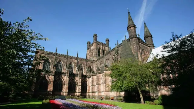 Archive exterior photograph of Chester Cathedral with trees and flower beds.