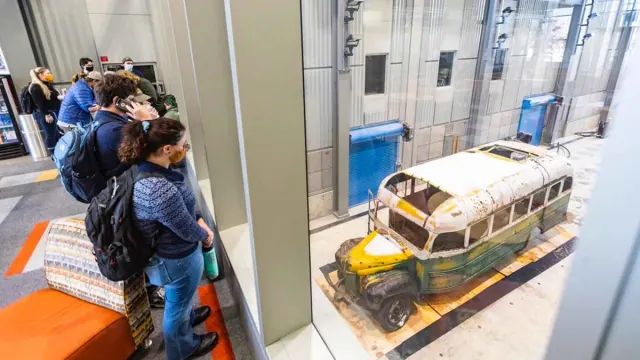 Bus 142 in place at a museum with visitors viewing it
