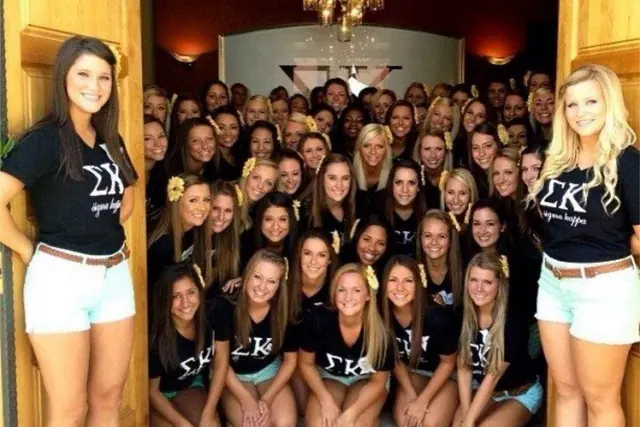 Archive group photograph of women posing inside a doorway in dark lettered shirts.