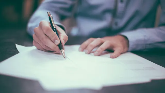 A person signing paperwork; illustrative photograph.