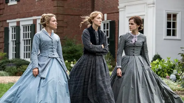 Three performers in period dresses beside a brick building
