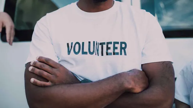Illustrative photograph of a person wearing a white shirt marked Volunteer.