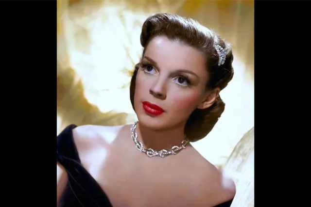 Color archive portrait of Judy Garland wearing a dark dress and necklace.
