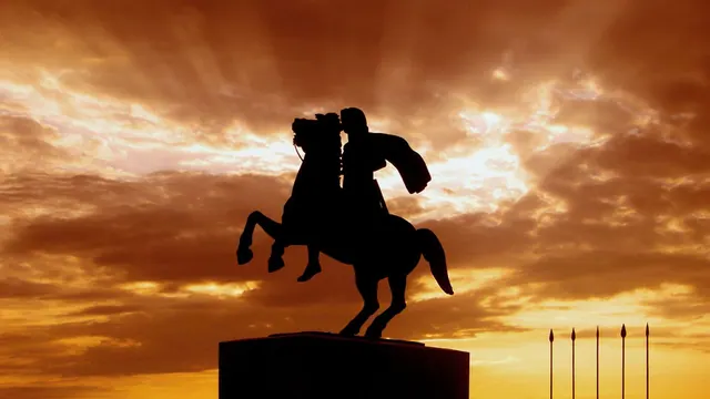 A silhouetted equestrian statue against a sunset
