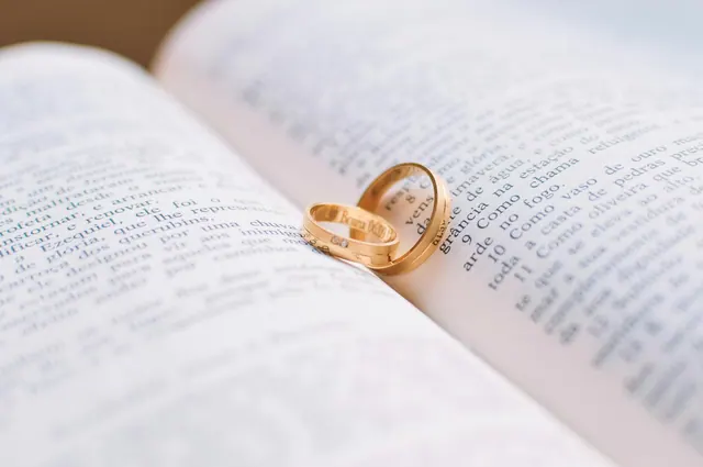 Illustrative photograph of two gold rings on an open book.