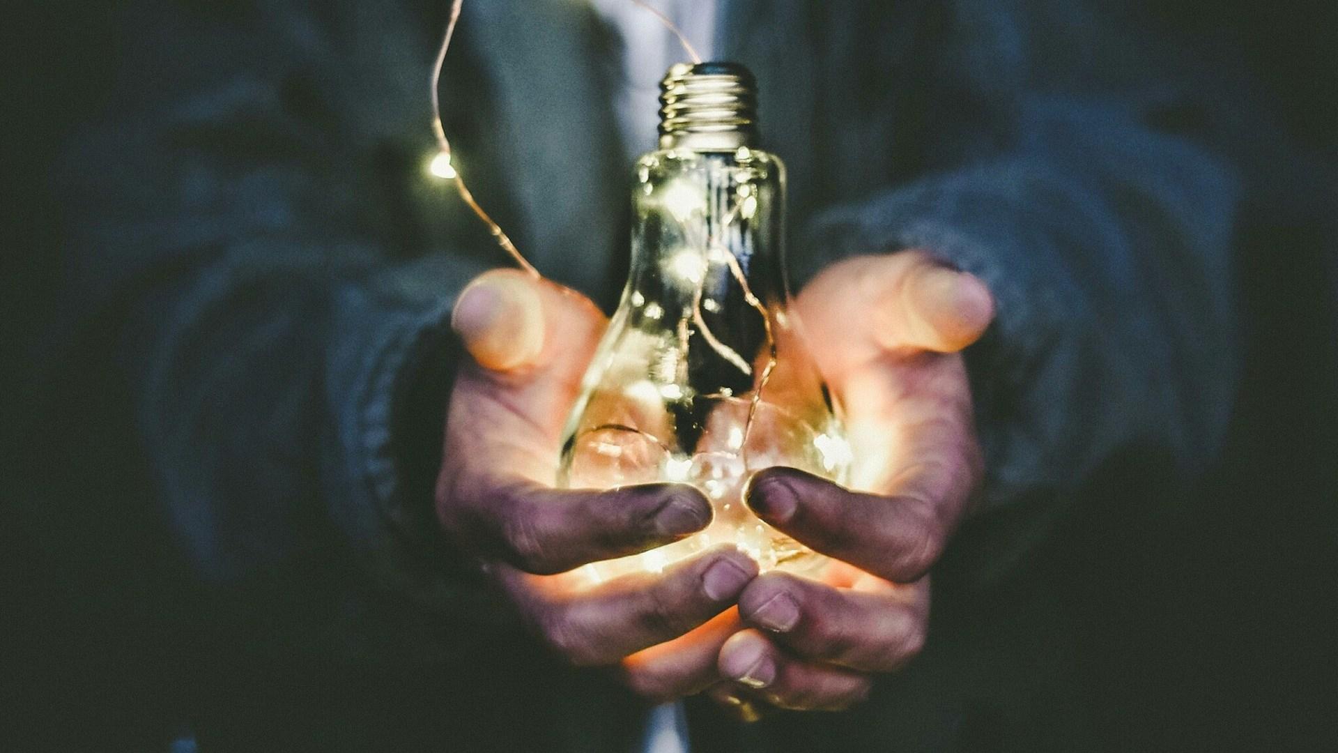 Hands holding an illuminated light bulb