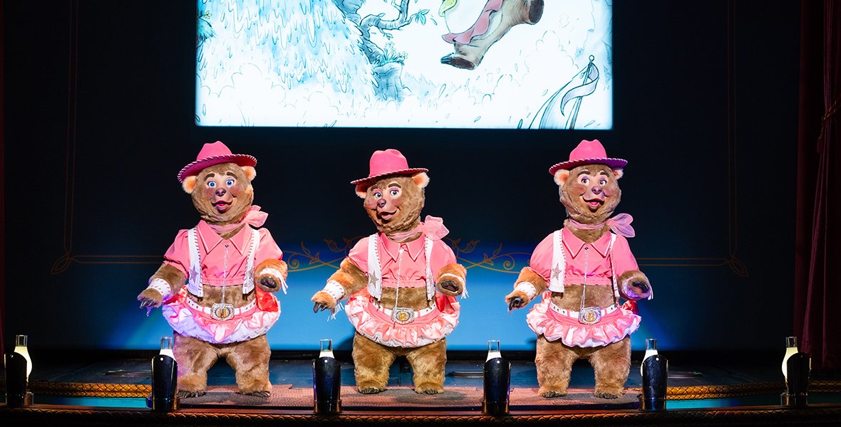 Three bear performers in matching pink costumes.