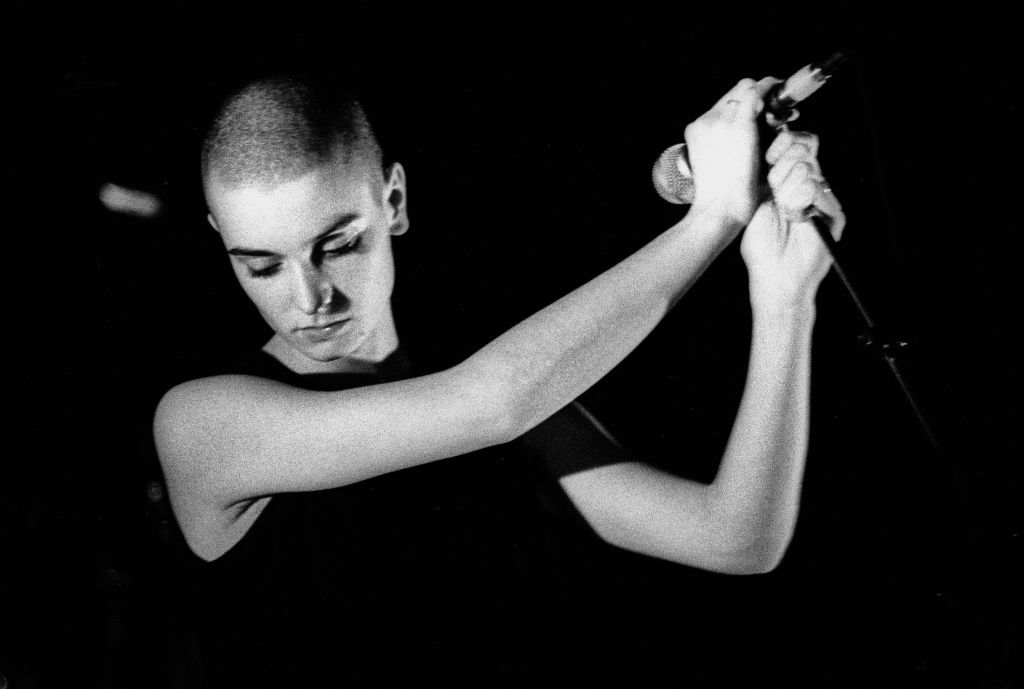Sinéad O’Connor singing with one arm raised