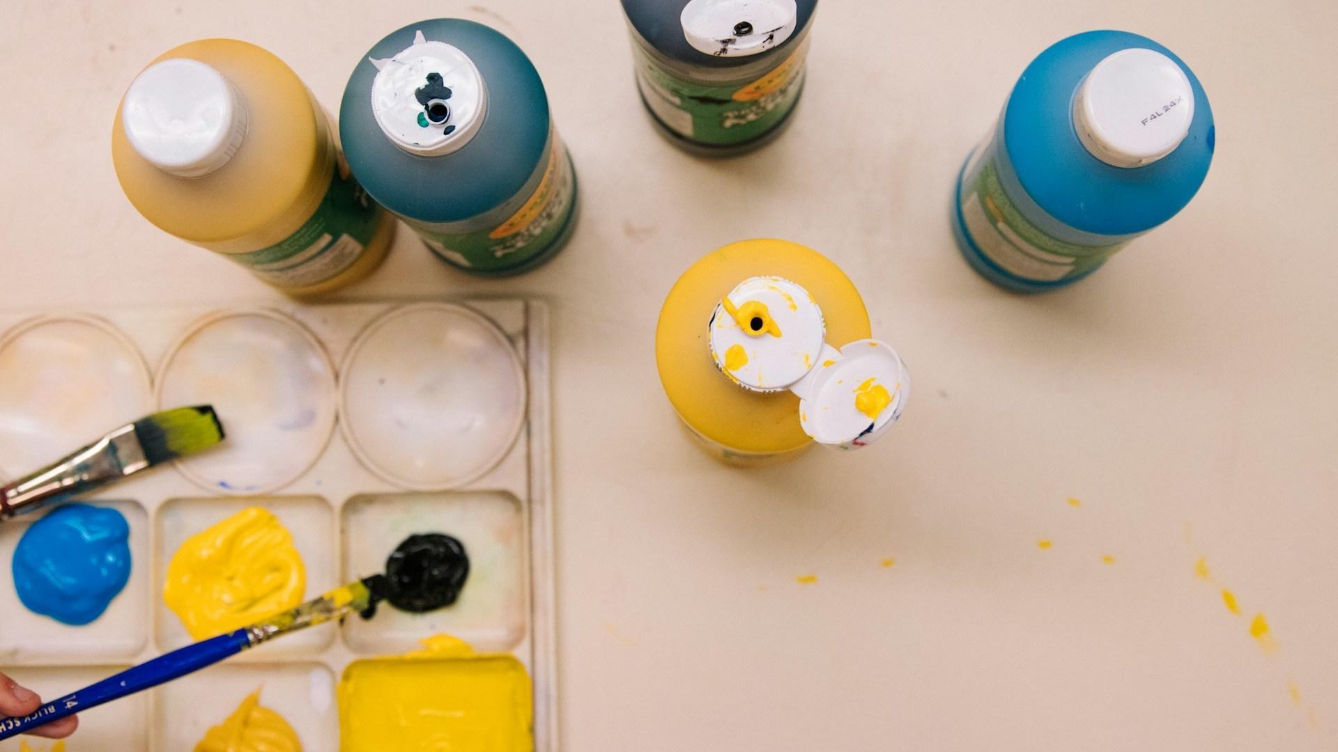 Paint containers and brushes on a work surface.