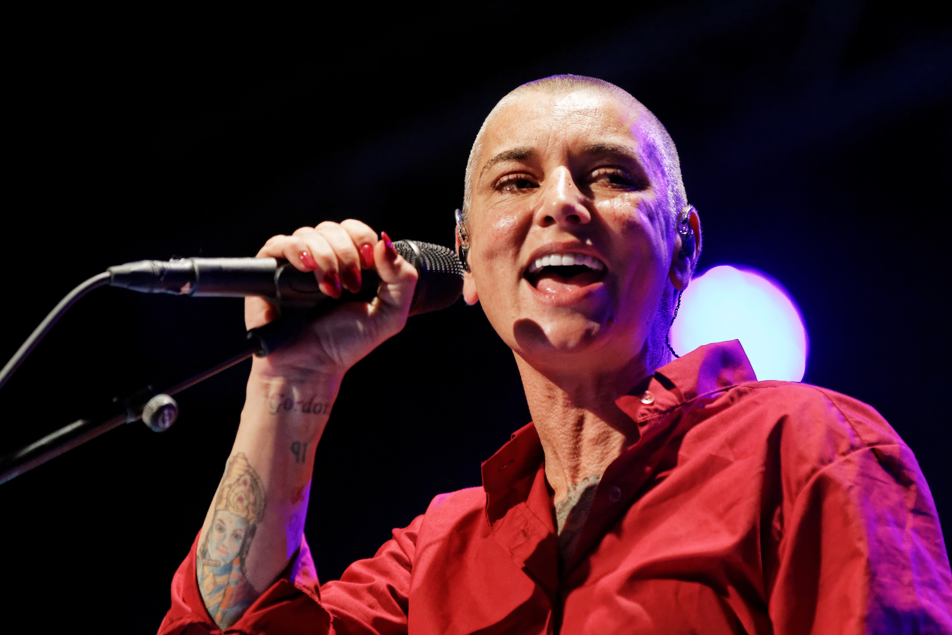 Sinéad O’Connor singing into a microphone