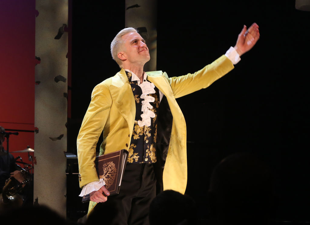 Gavin Creel performing onstage in a yellow jacket