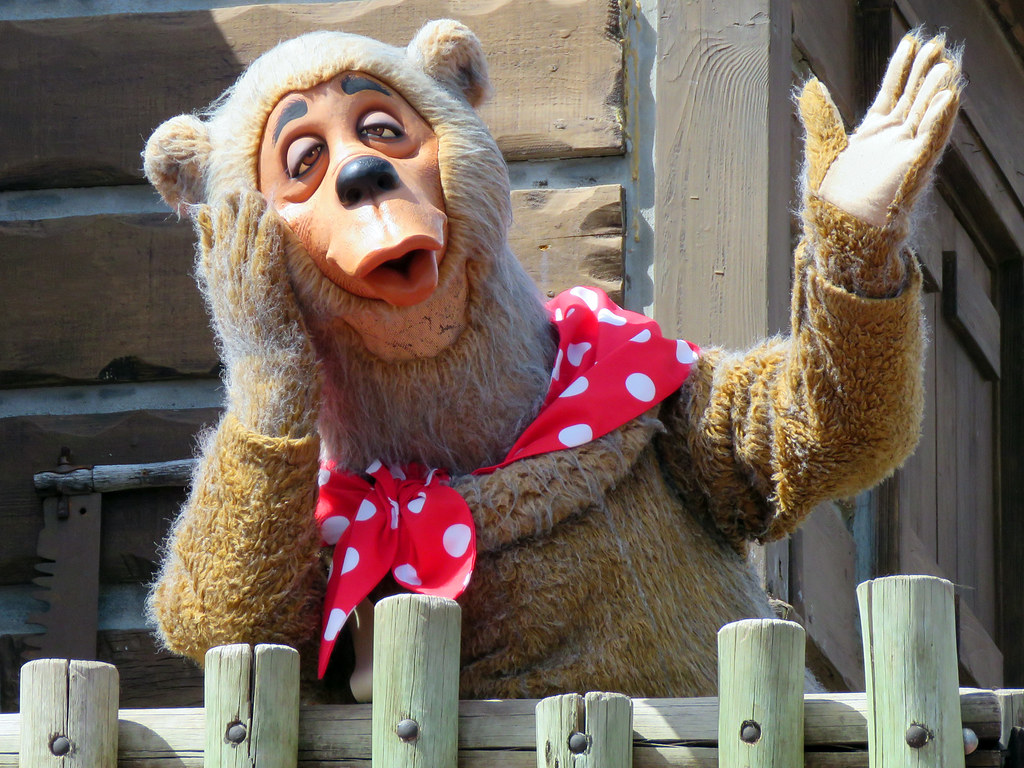 A bear character in a red polka-dot scarf.