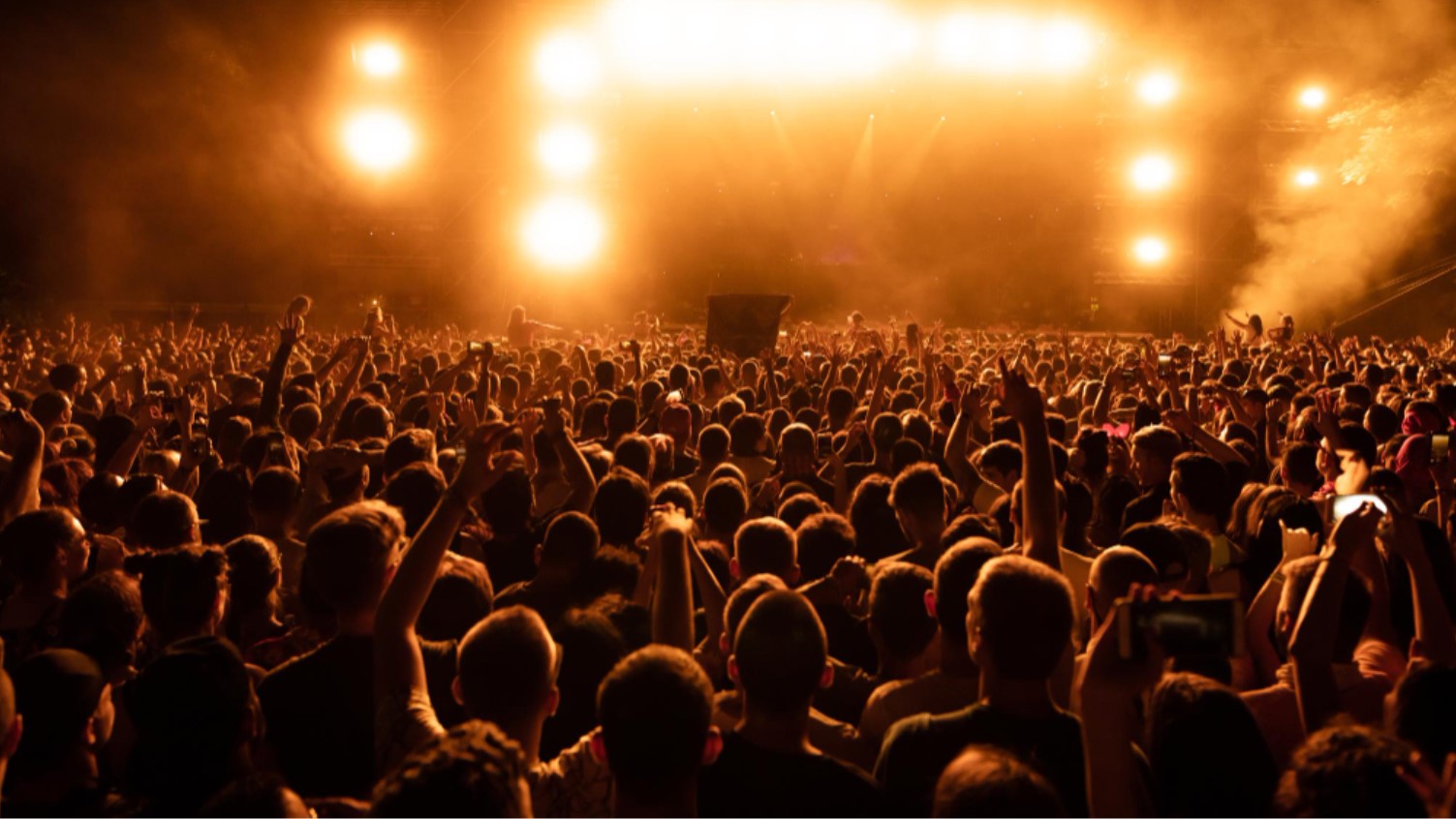 A crowd beneath concert stage lights; illustrative photograph.