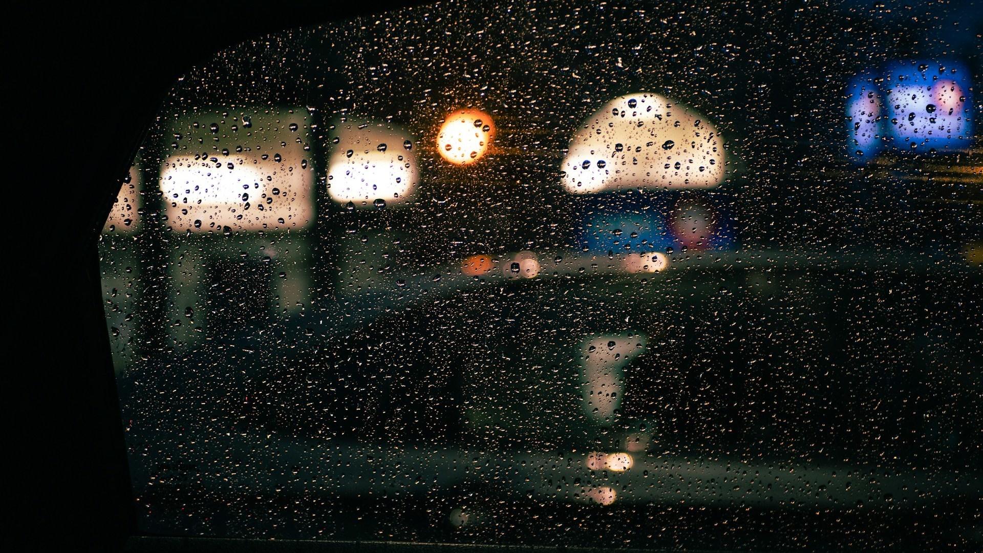 Night lights seen through a rain-covered vehicle window